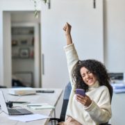 excited young lady holding a phone with her fist in the air